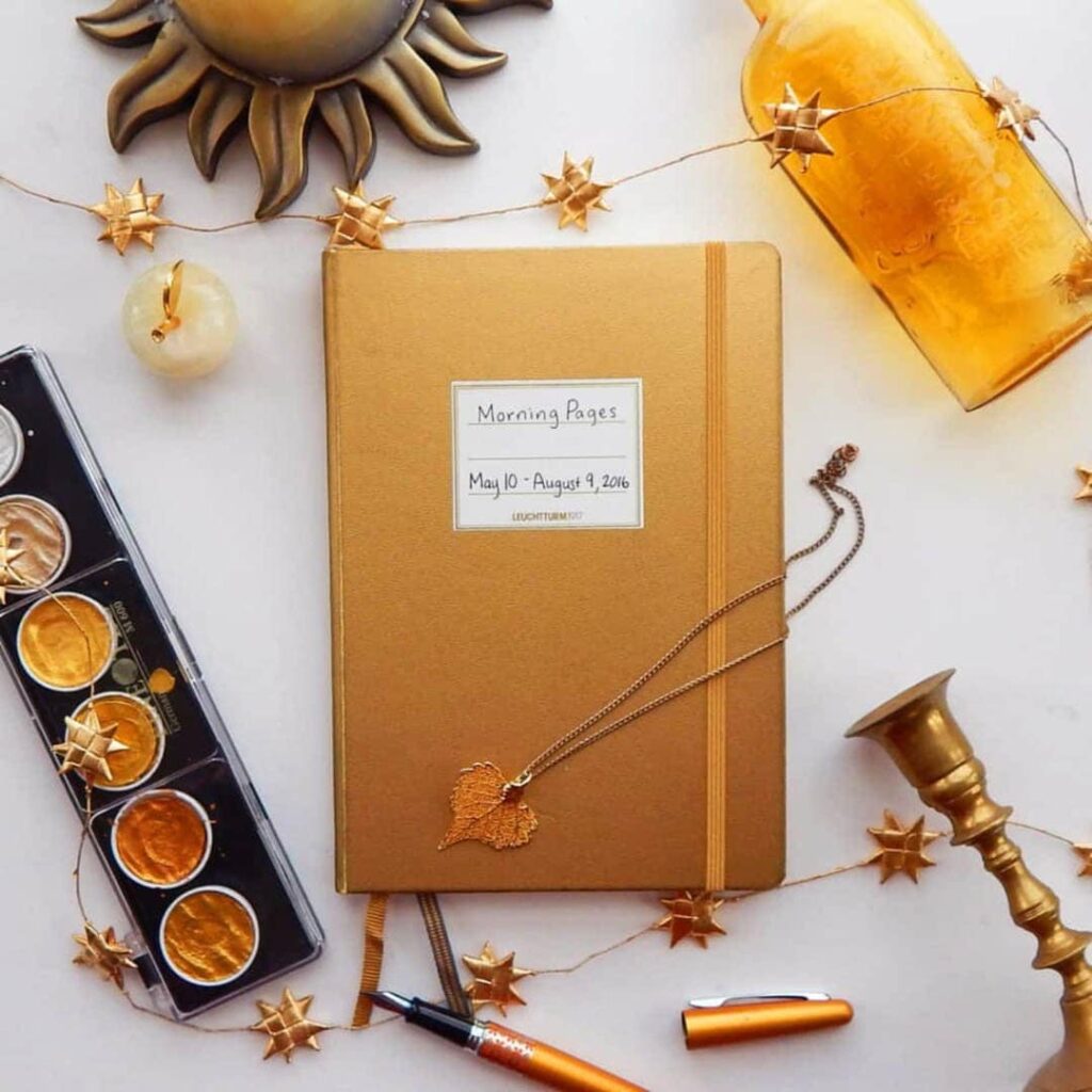 metallic gold bullet journal with paints and gold bottle