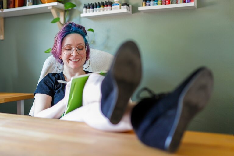 Image of Shelby sitting at her desk with her legs kicked up and journal in her lap.