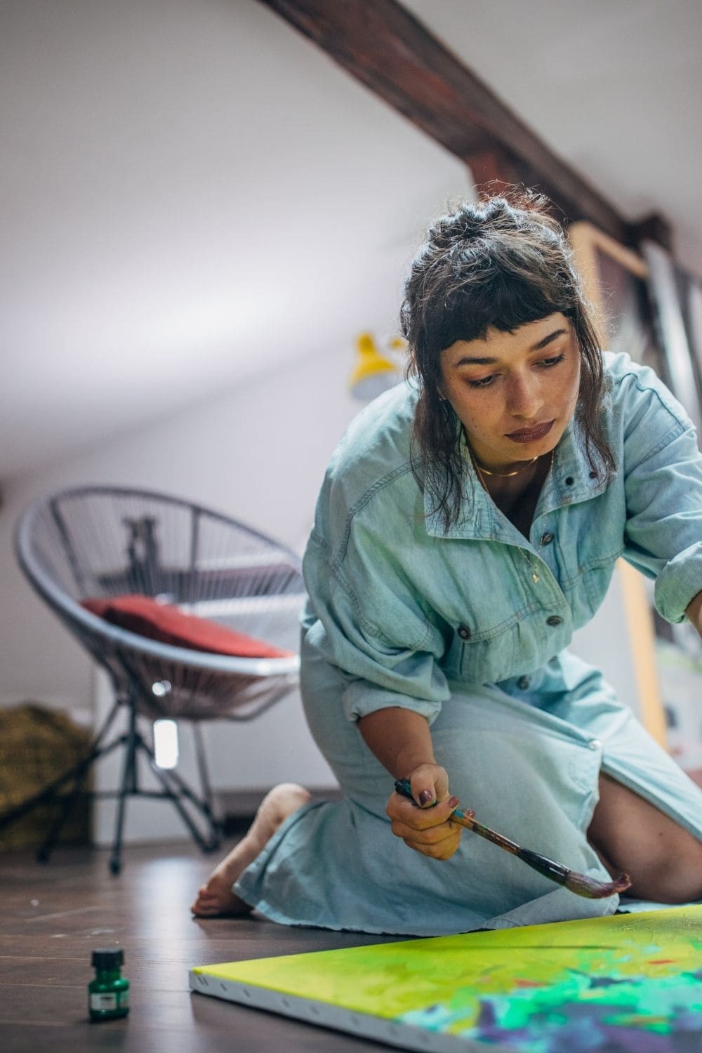 image of harmful myths about artists with woman painting on a canvas sitting on the floor 
