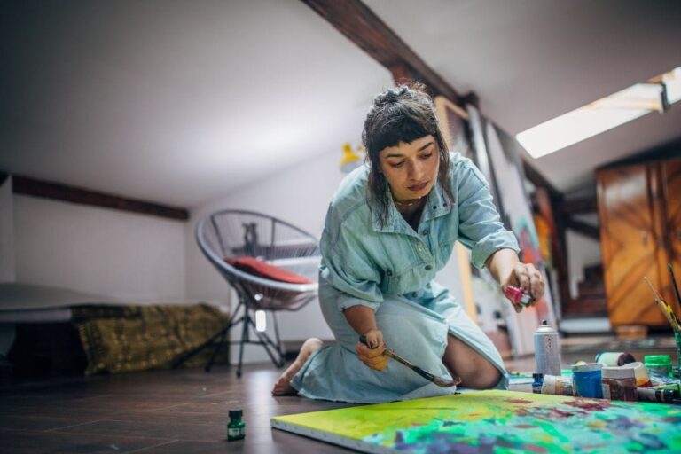 woman painting on a canvas on the floor